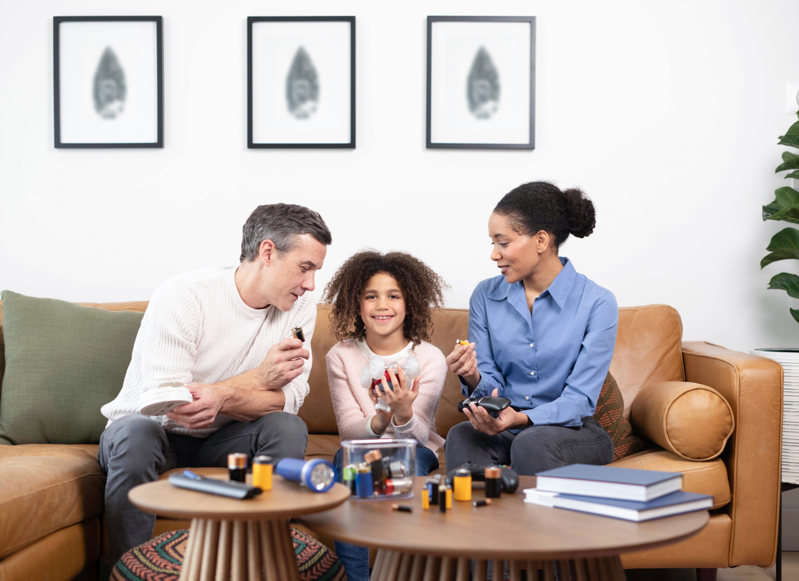 mom, dad and daughter recycling batteries