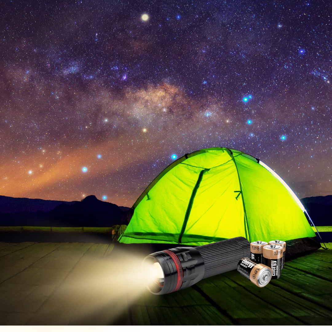 A tent under starry sky with batteries and a flashlight next to it.