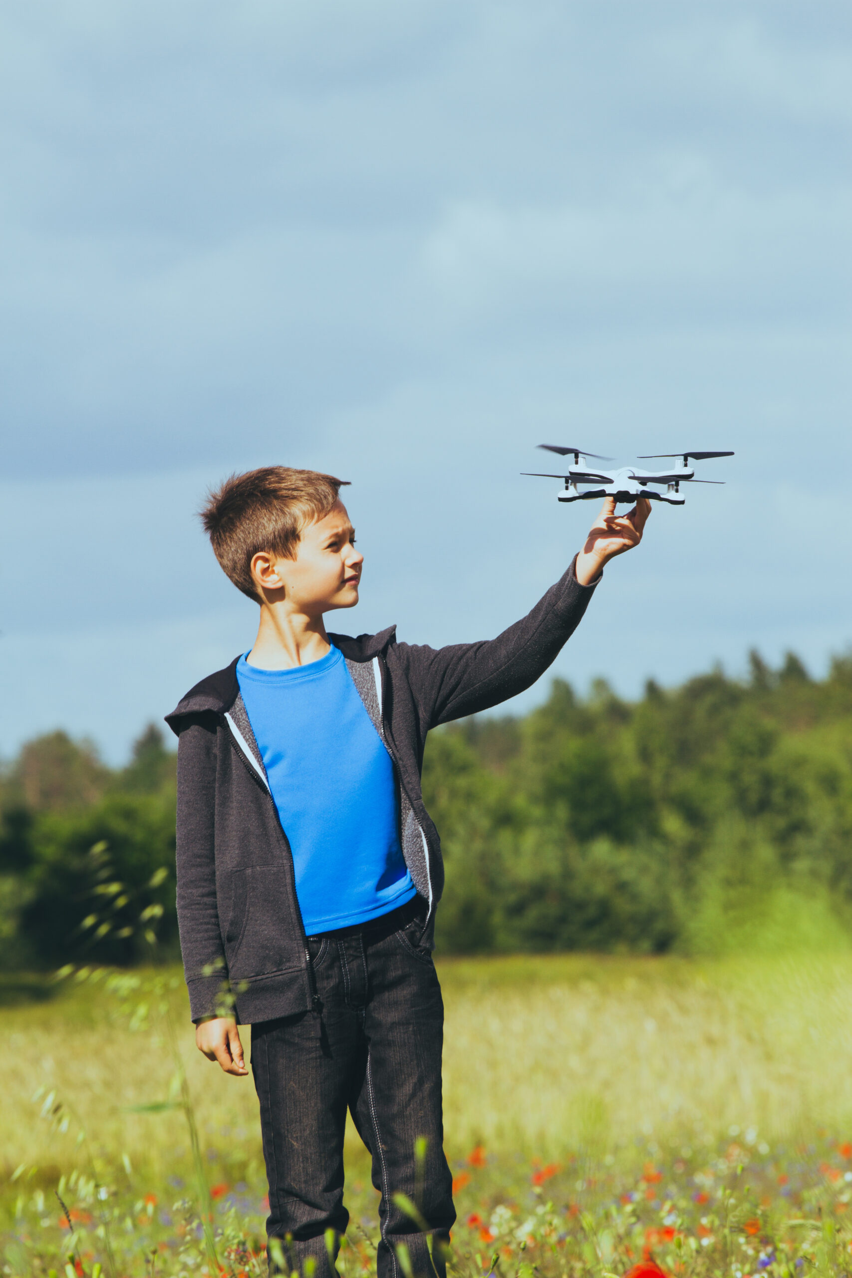 Child playing with drone outdoors at summer day
